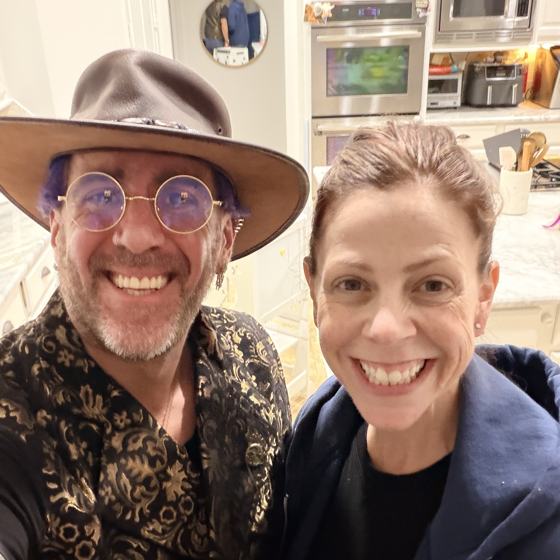 Mike in a wide-brim hat and round glasses, with his wife